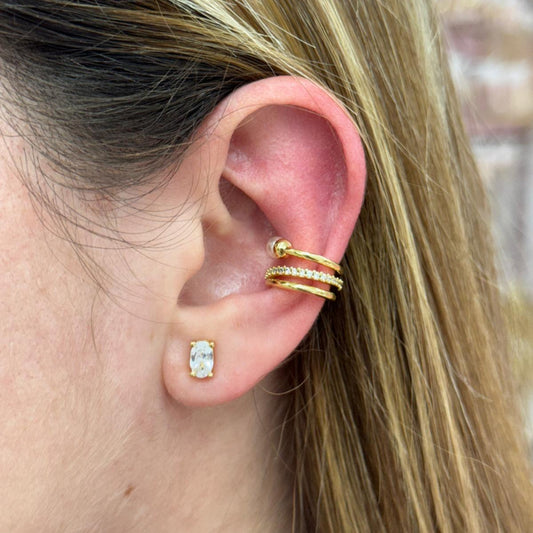 Close-up of an ear wearing gold earrings with a blurred background