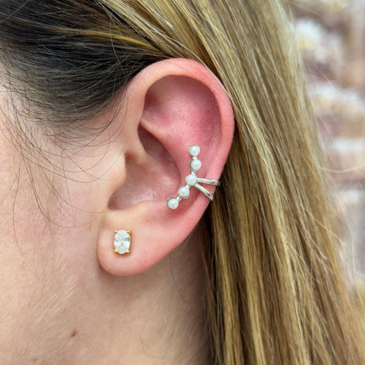 Close-up of an ear with pearl and diamond earrings against a blurred background