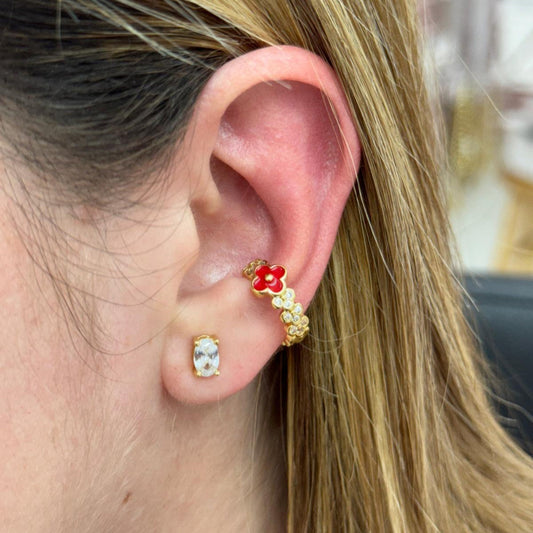 Close-up of a person's ear wearing gold and red earrings.