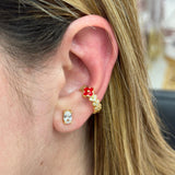 Close-up of a person's ear wearing gold and red earrings.