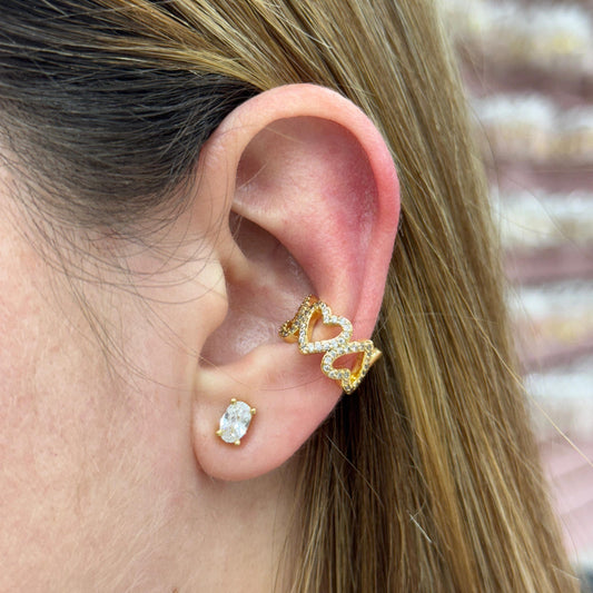 Close-up of a person wearing gold and red gemstone earrings with a blurred background